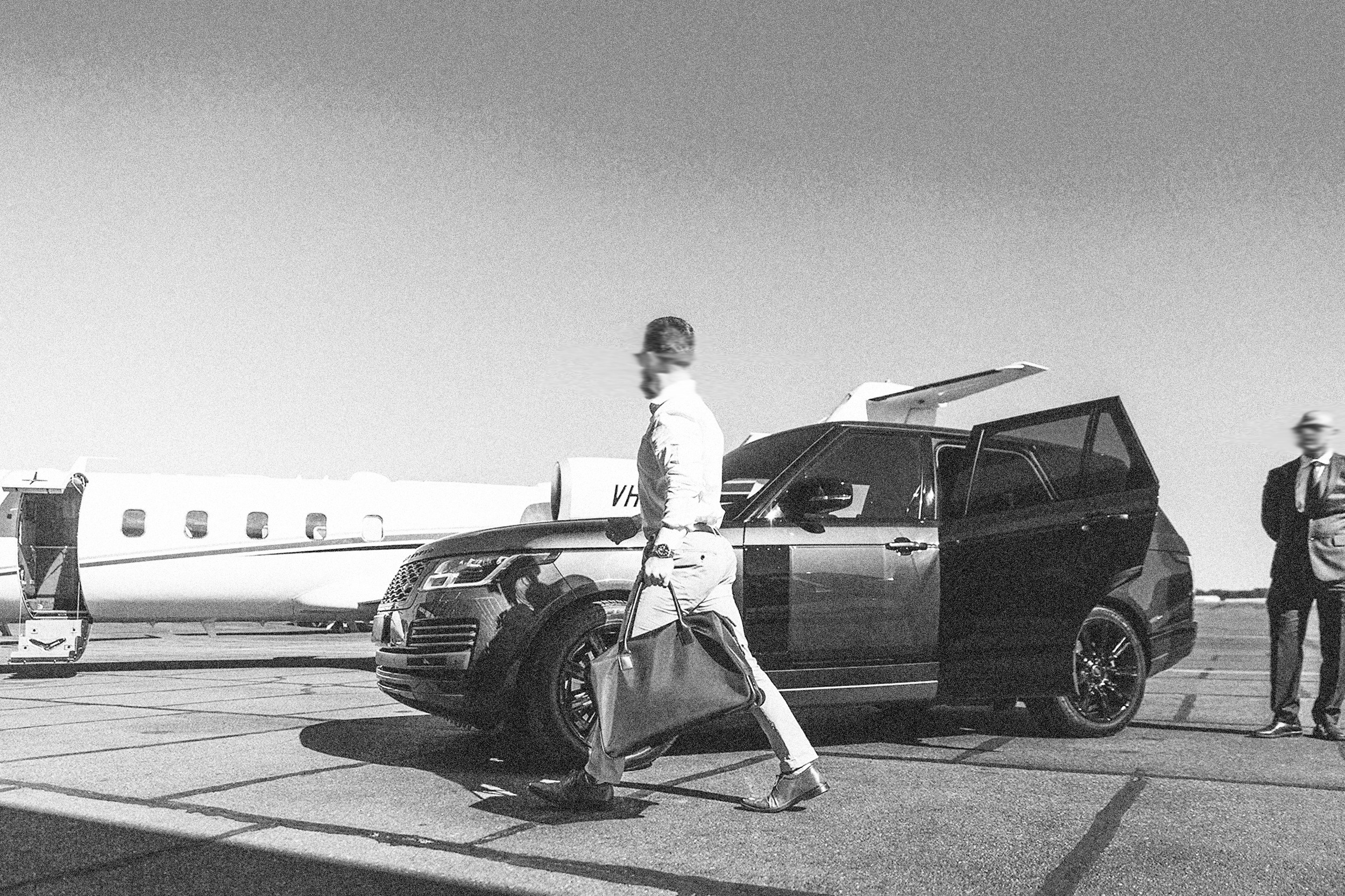 Principal walking from a private jet to a waiting vehicle, with a close protection officer standing by