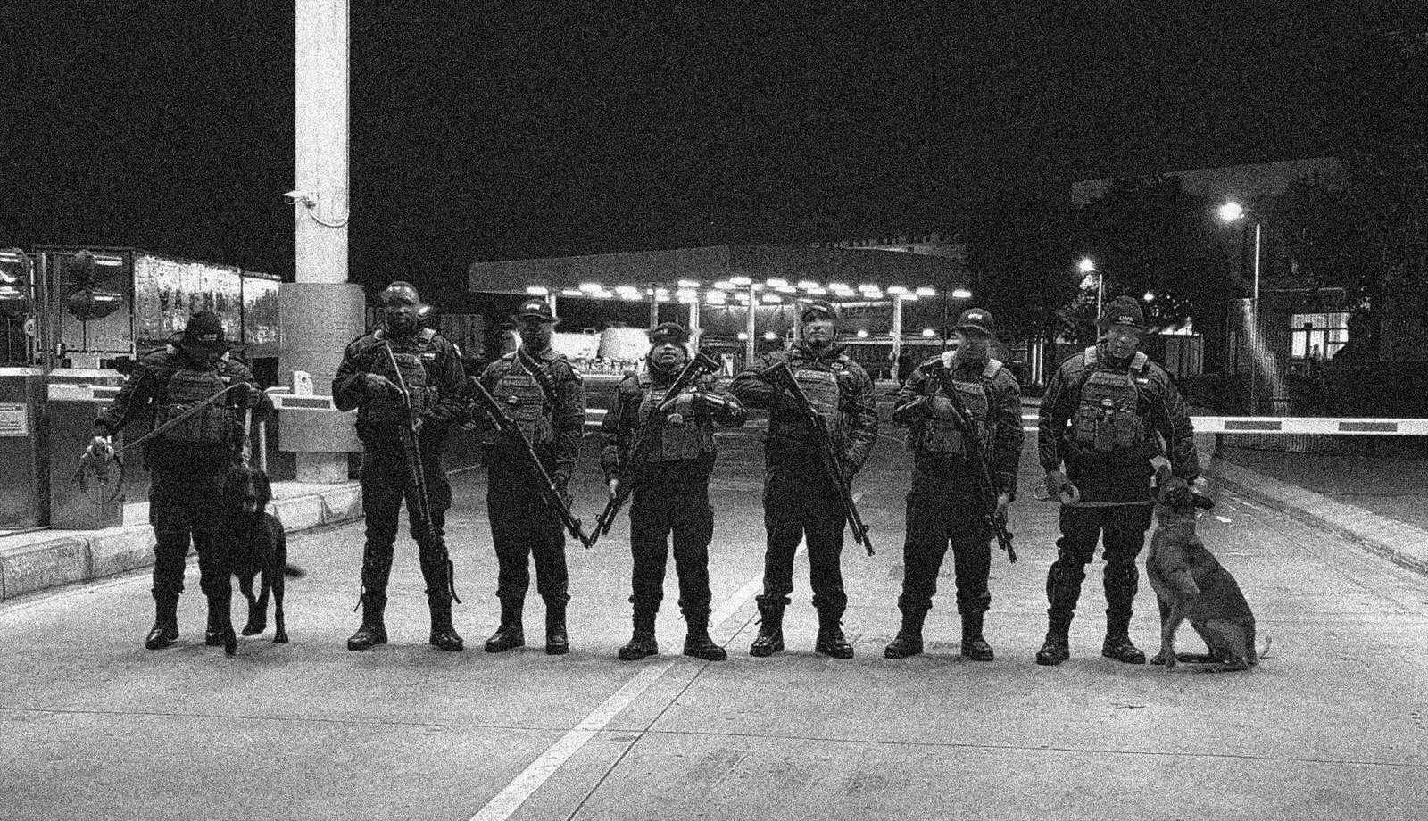 ONE tactical officers and K9 handlers lined up at a site gate at night
